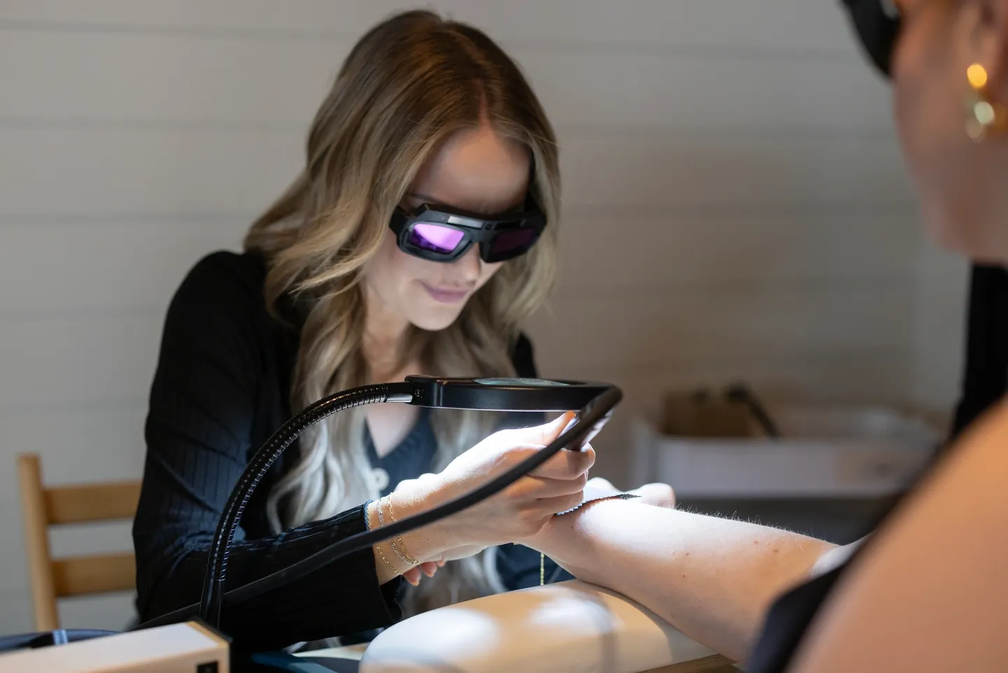 Woman wearing VR headset interacting with a device using a magnifying lamp.