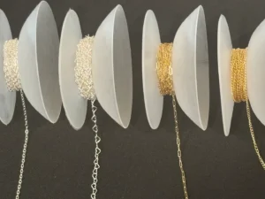 Delicate necklaces displayed on white circular holders against a dark background.